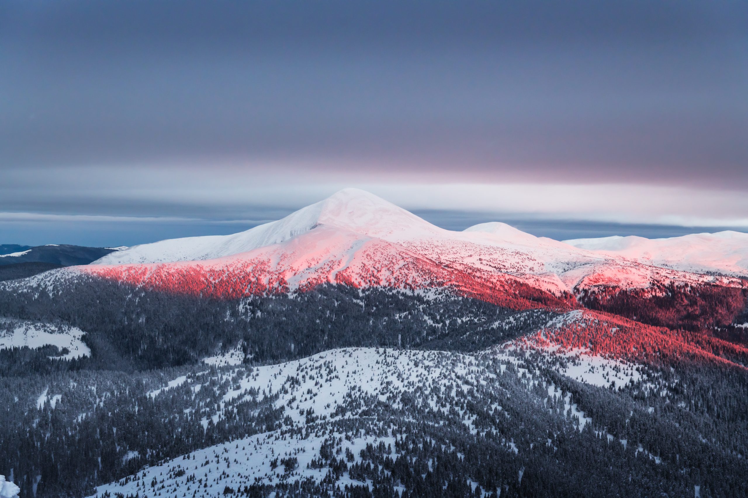 Snow-covered mountain peak illuminated by soft pink sunlight, symbolising clarity, mastery, and hyper competence.
